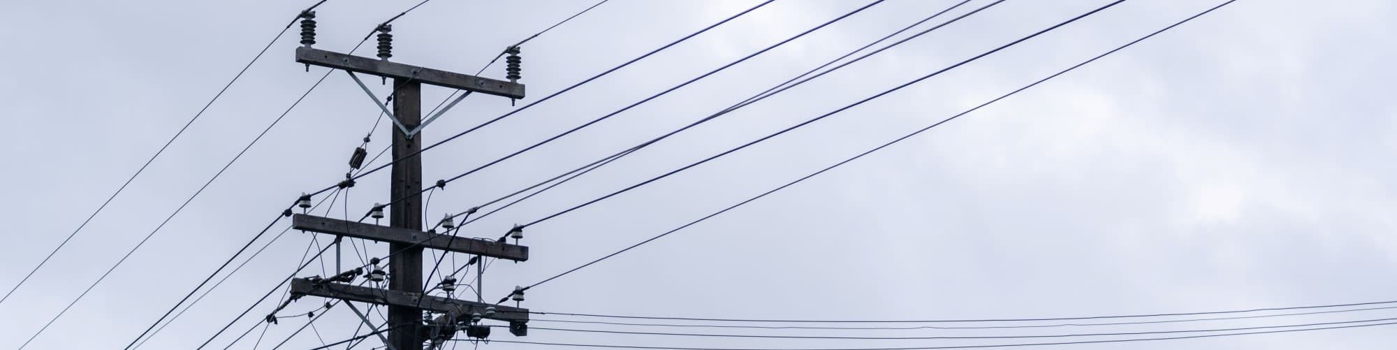Top section of power pole with power lines running across 