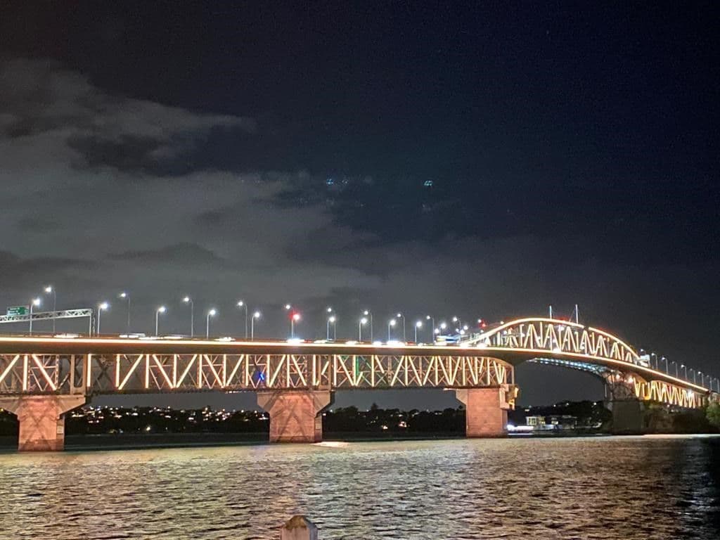 Auckland harbour bridge lit up in red and yellow at night