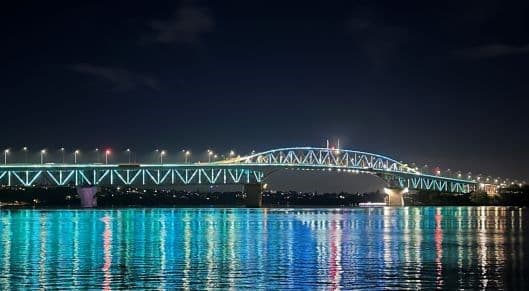 Auckland harbour bridge lit up in blue at night