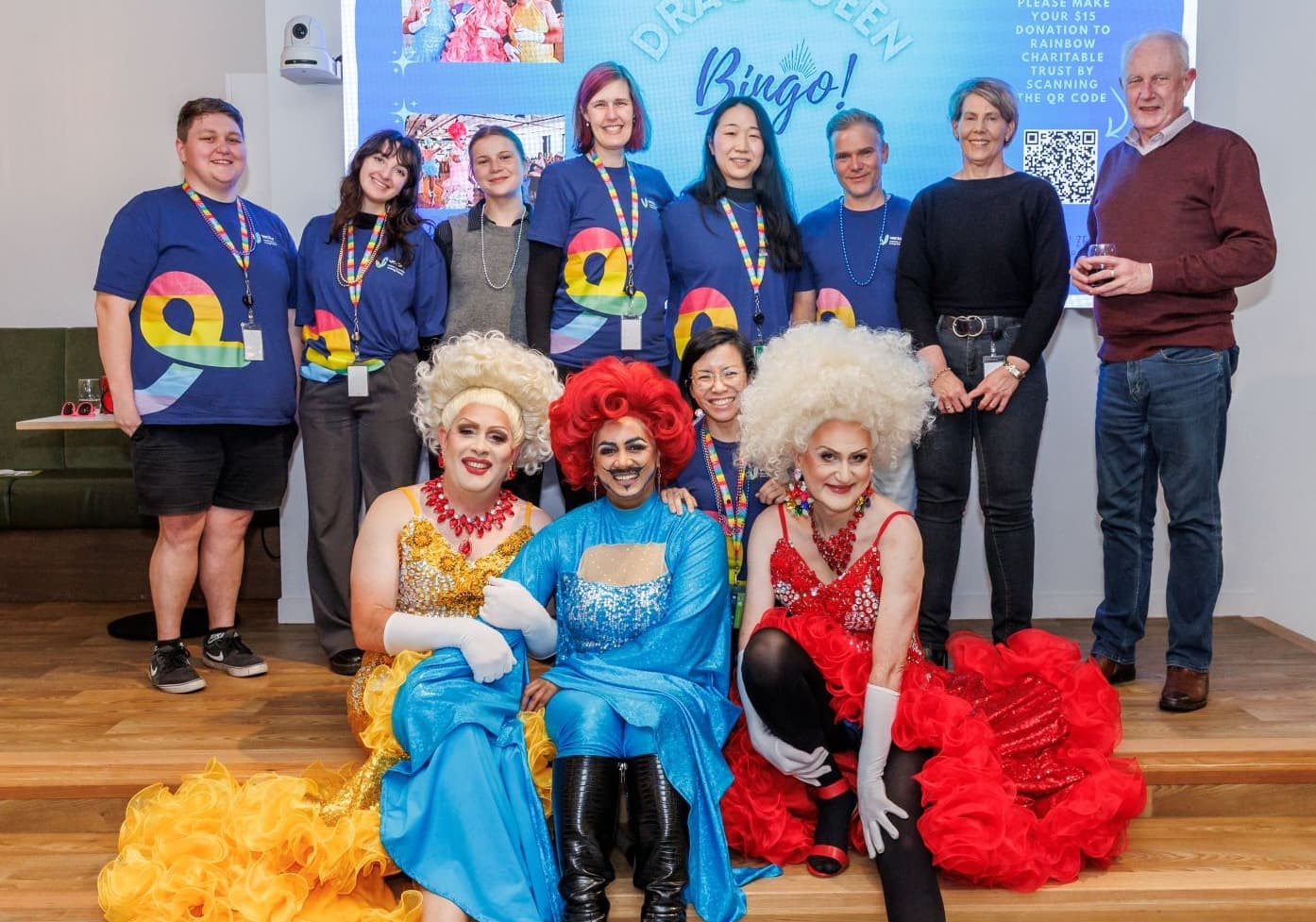 three drag queens in the foreground and the some of the Vector diversity and inclusion team in the background during a Drag Queen Bingo event