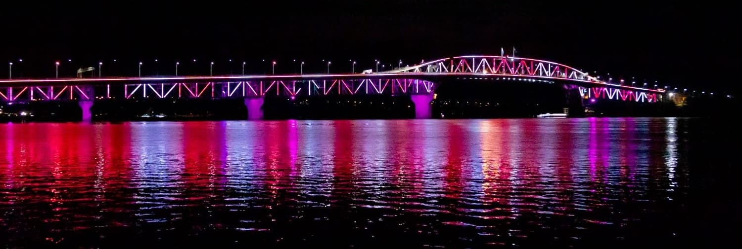 Auckland harbor bridge lit up by Vector Lights at night.