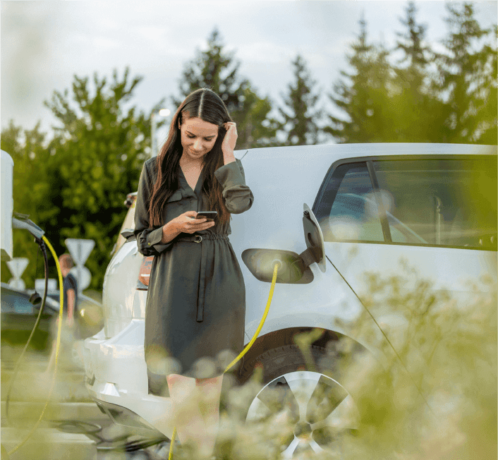 Woman standing by ev looking at her phone