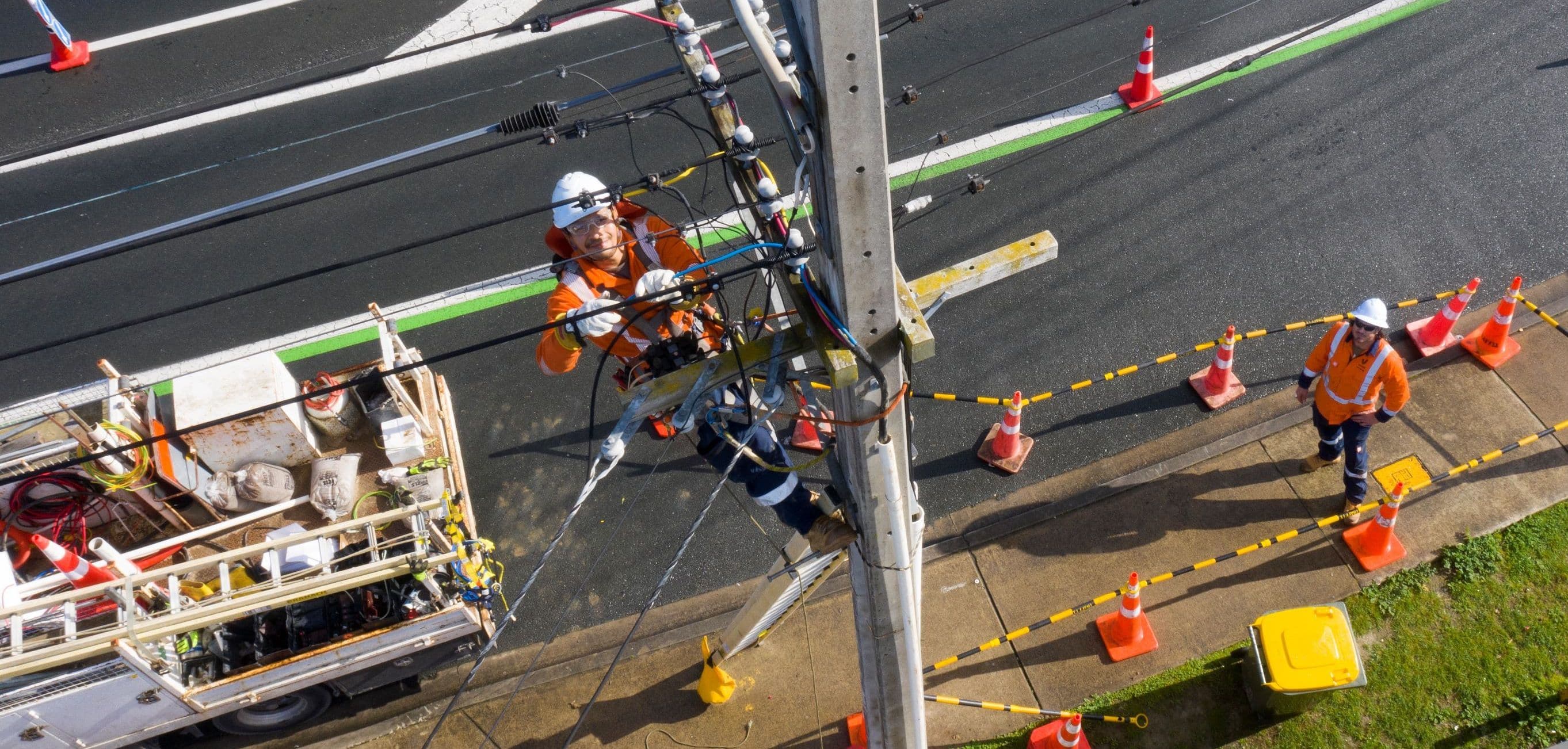 Birdseye shot looking down at person working on power pole and lines